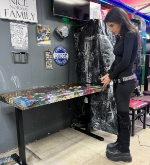 The maker standing beside a colorful resin table in the studio