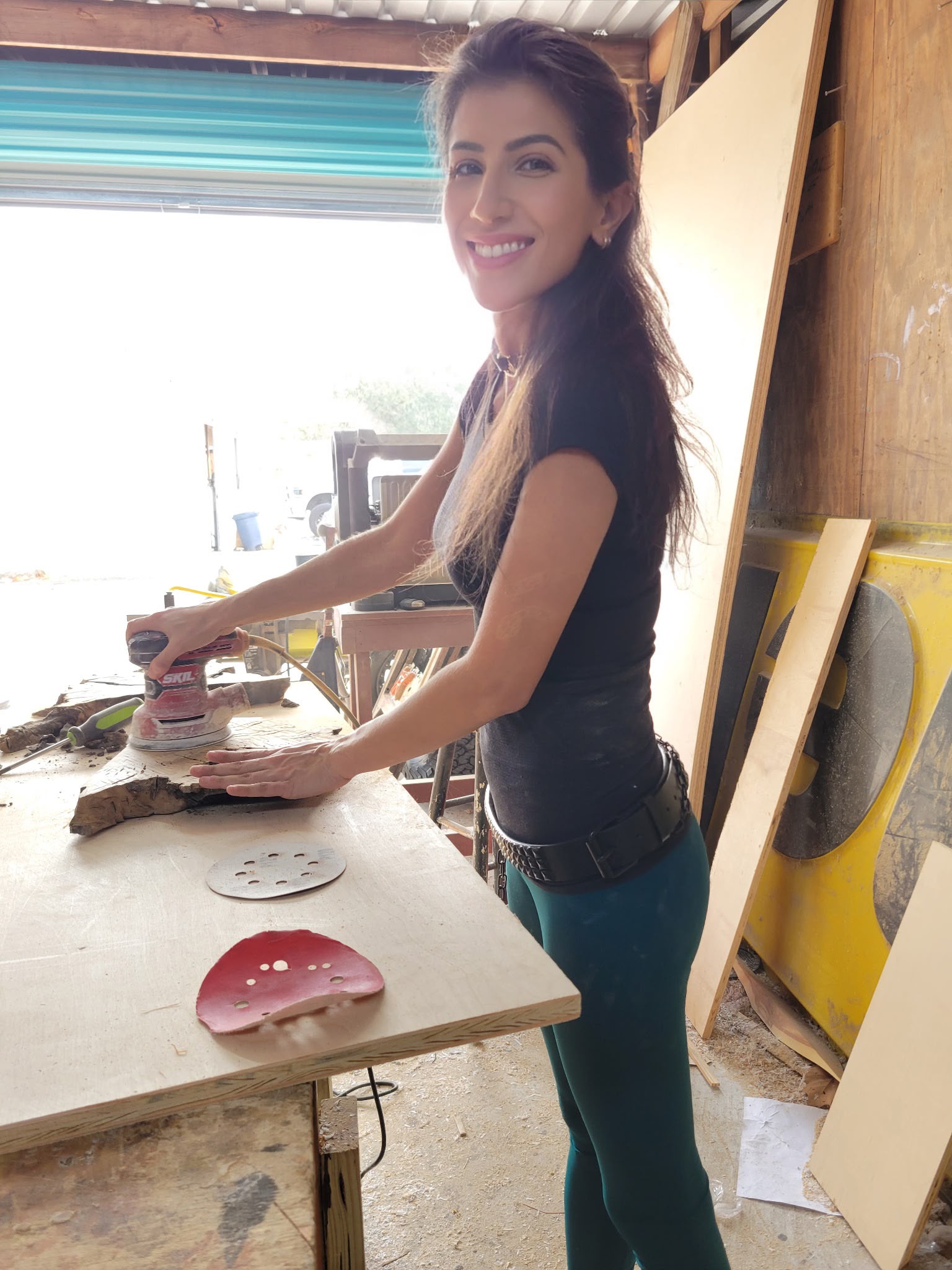 The maker sanding a live-edge wood piece in her workshop